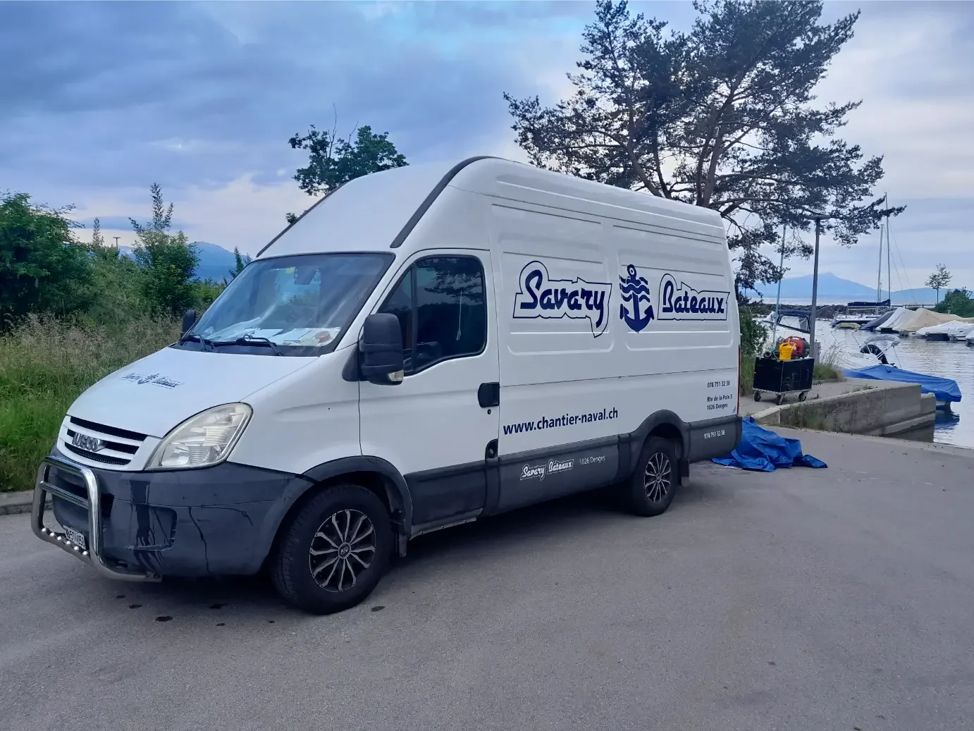 Camion blanc Savary Bateaux près d'un quai avec des bateaux.
