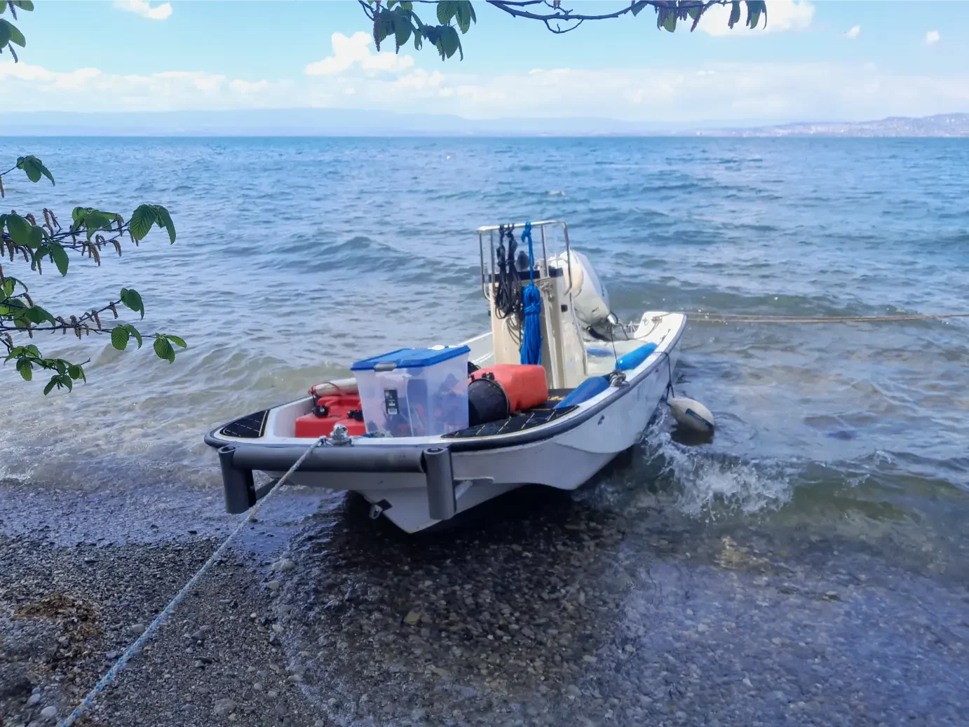 Petit bateau de pêche accosté sur la rive d'un lac calme.