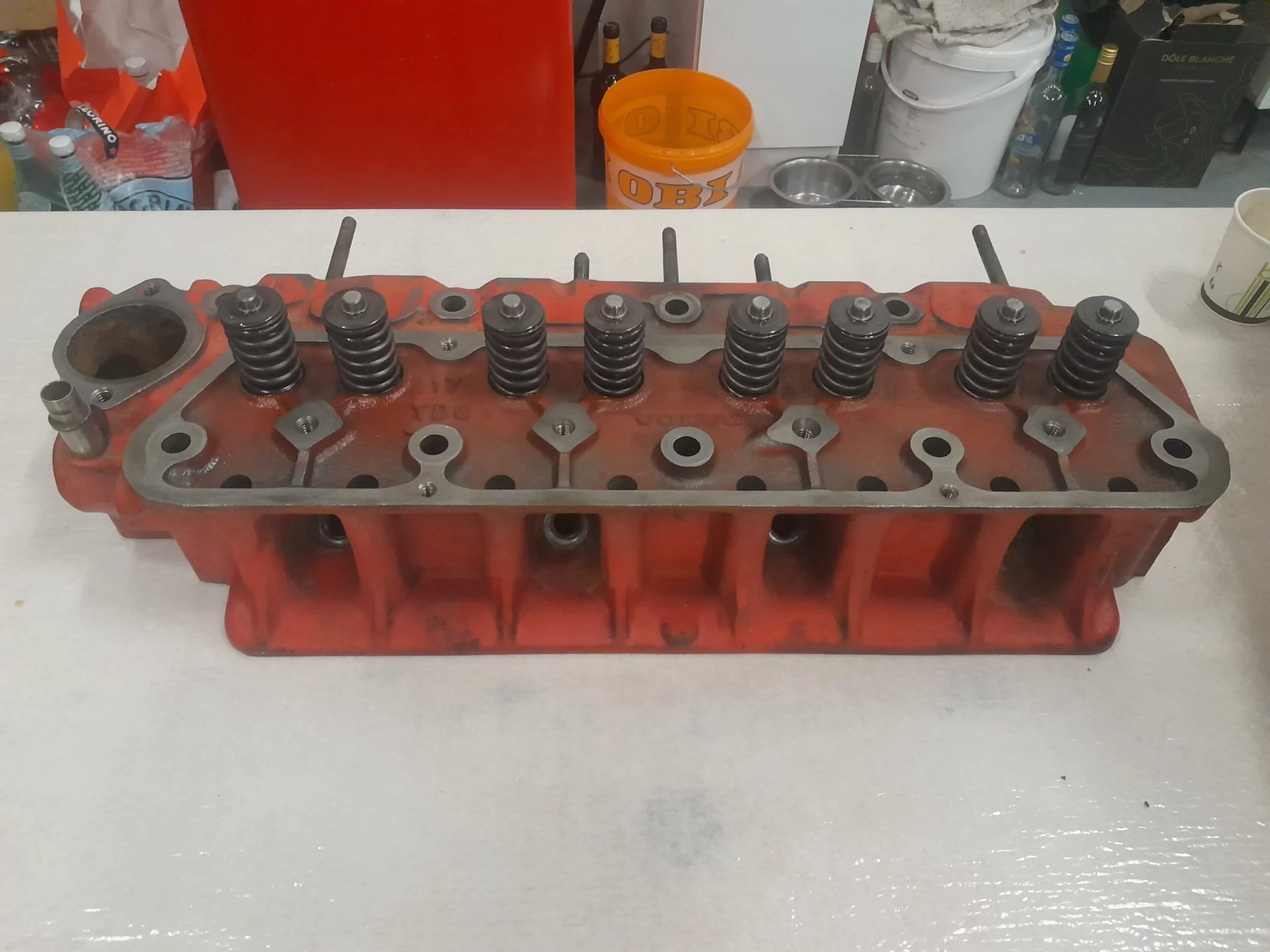 Culasse de moteur rouge avec ressorts métalliques exposée sur une table