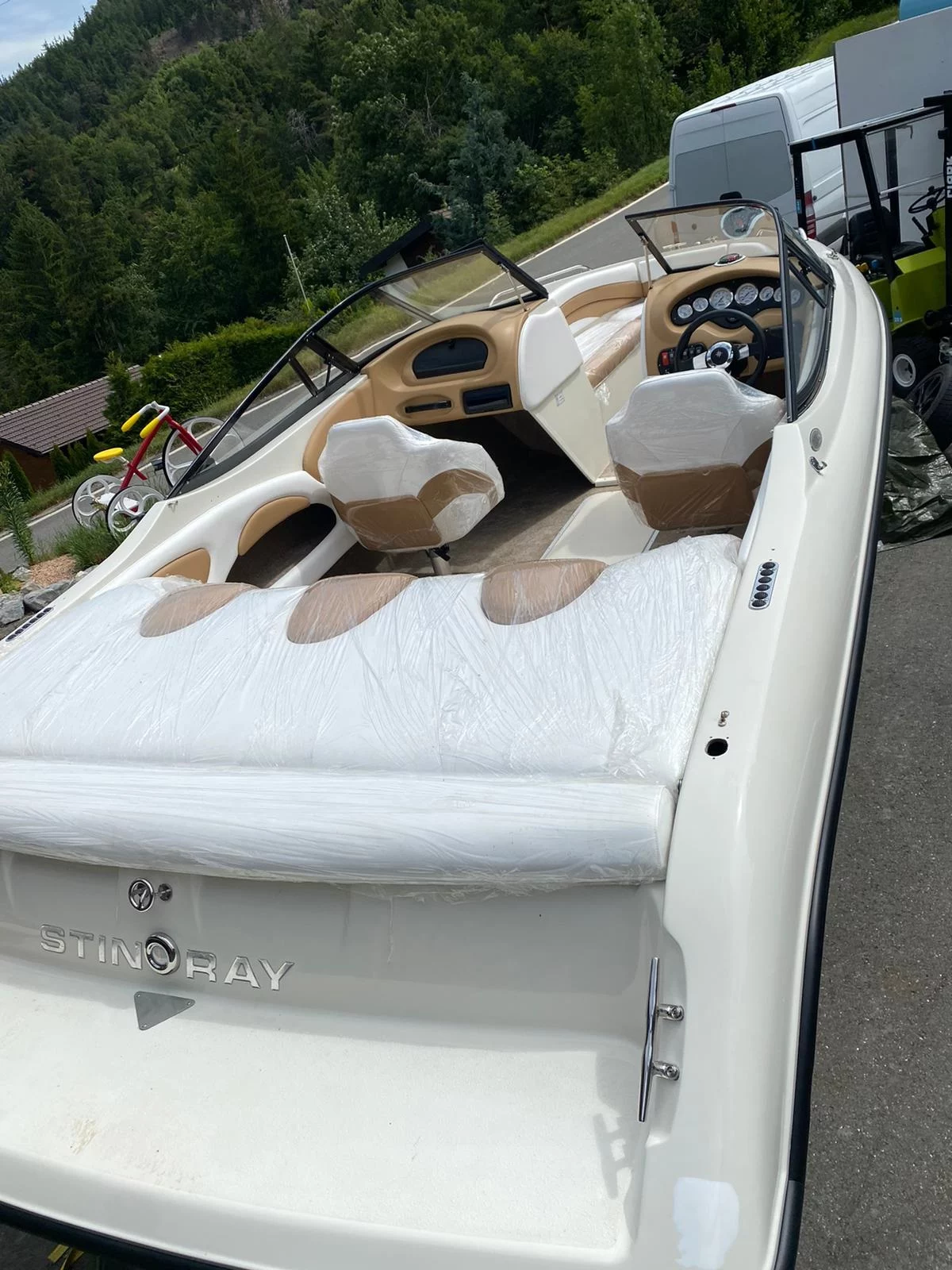 Bateau de plaisance sur remorque en plein air, sièges recouverts.