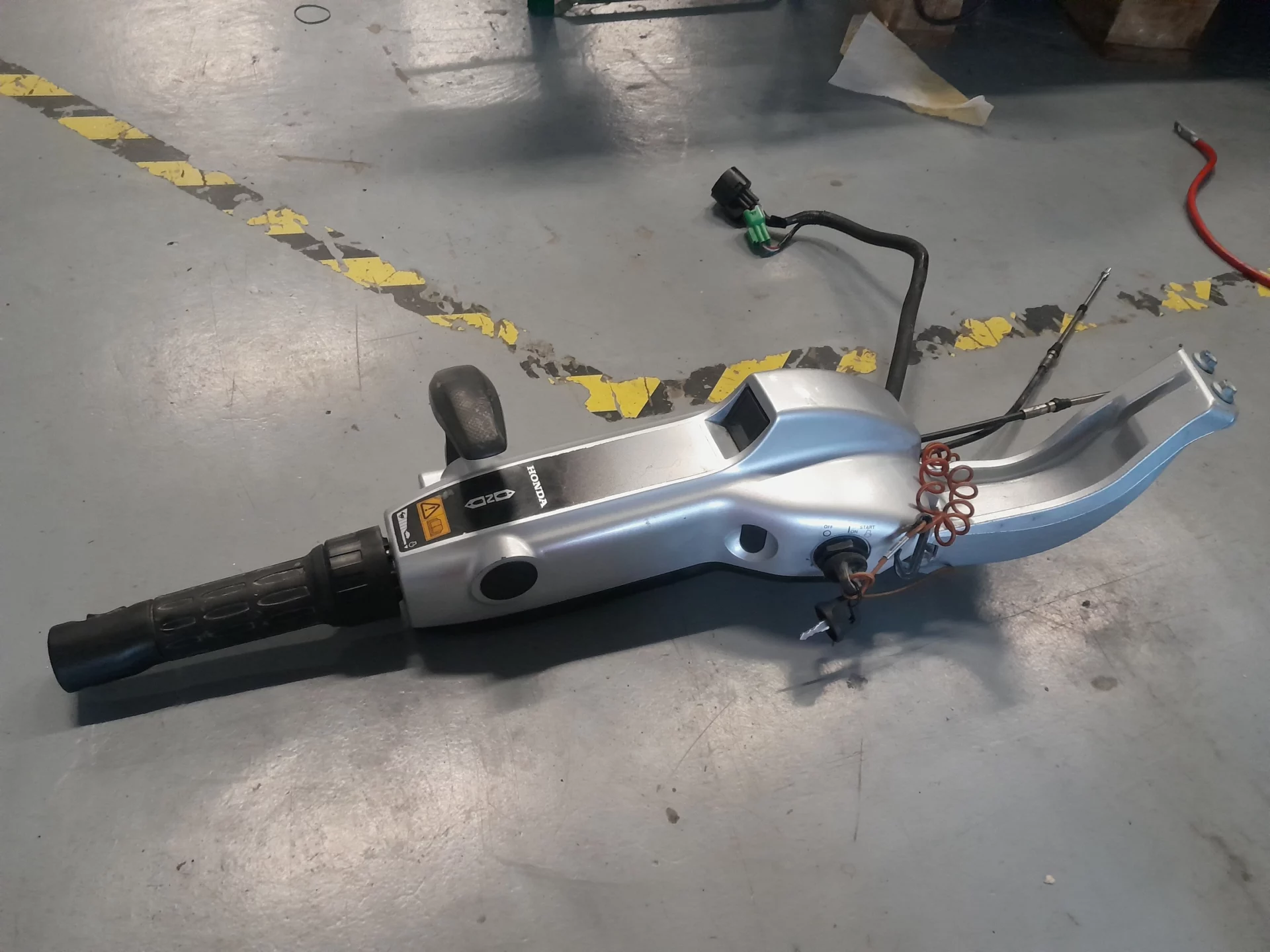 Poignée de trottinette électrique posée sur le sol d'un atelier.