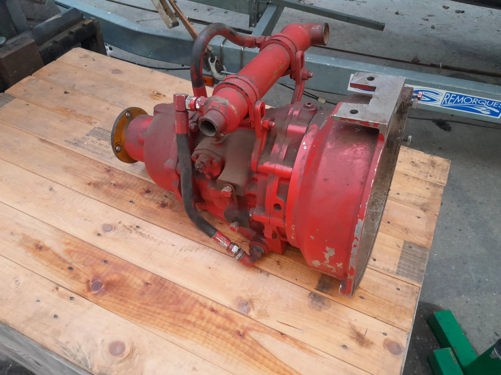 Pompe hydraulique rouge posée sur une palette en bois