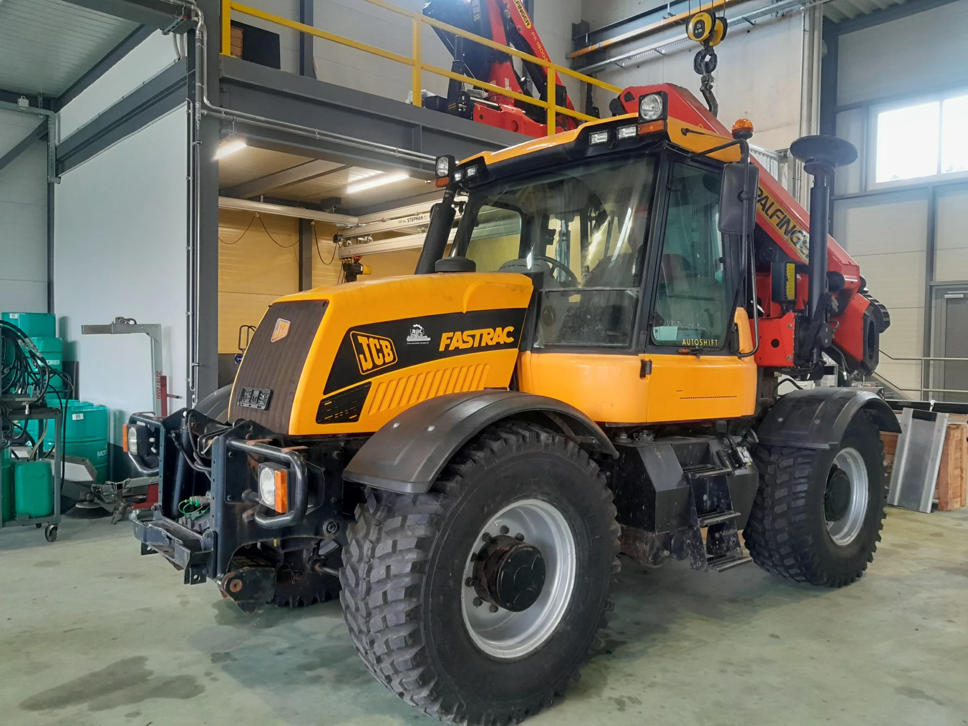 Tracteur JCB Fastrac jaune dans un atelier de réparation.